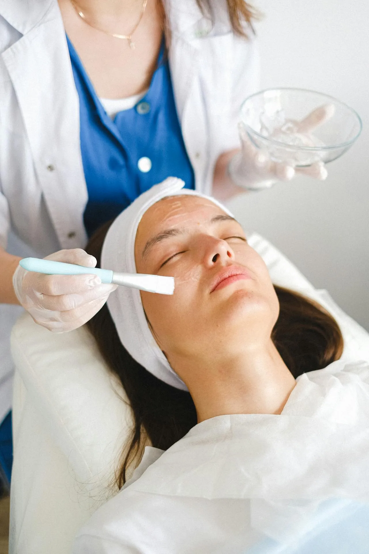 Esthetician applying facial mask on client